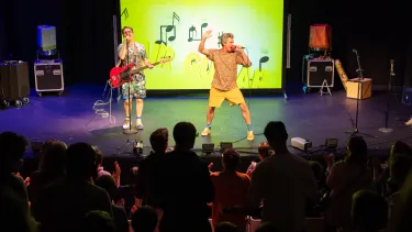 Two men on the stage, singing and playing guitar.